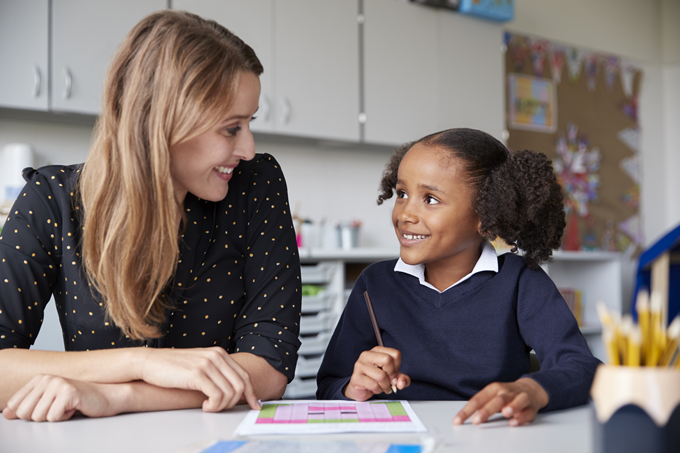 Teacher and child smiling whilst working