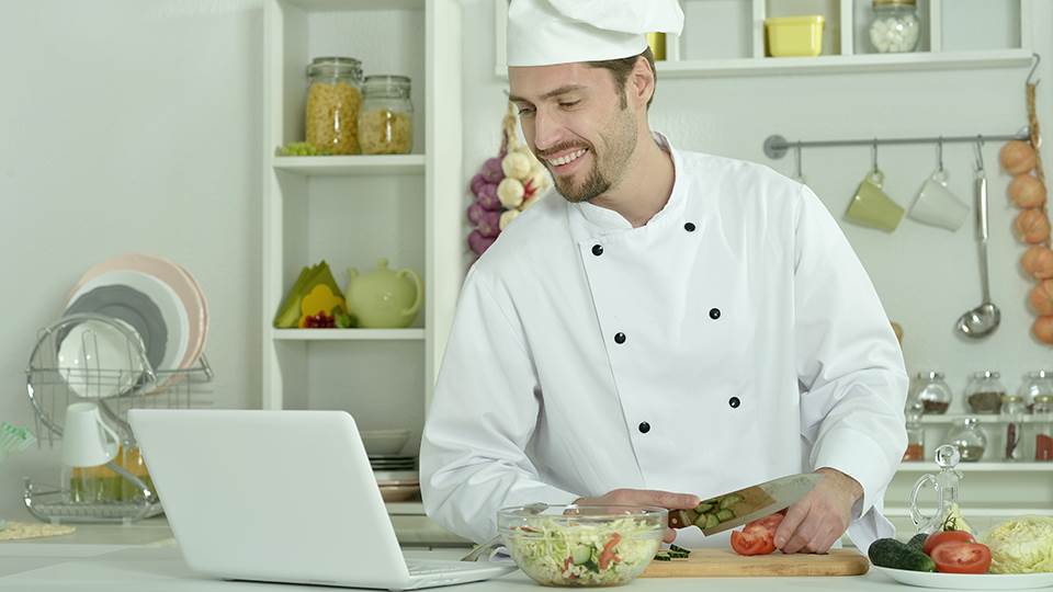chef in kitchen with computer